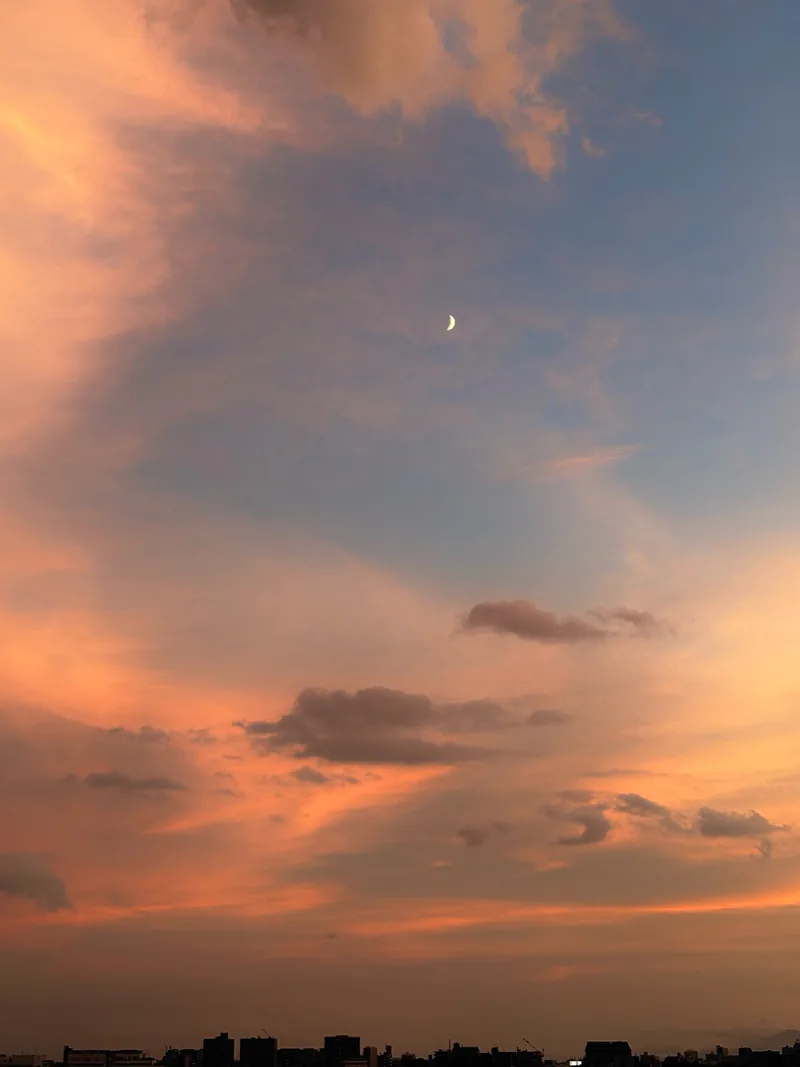 夕焼けに染まる雲と小さな月
