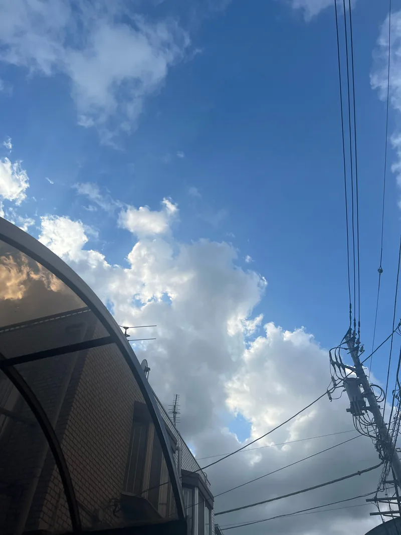 青空と雲、建物と電線が写る朝の空